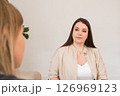 a female psychologist holds a face-to-face meeting with a client in her office. woman listens intently. Their discussion seems focused and serious, highlighting their engaged expressions. 126969123