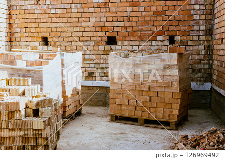 Building materials are on floor, stack red bricks. Production high-quality ceramic brick matte, reddish, porous fracture. Brick used for laying foundation. Purchase building material at hardware store Building materials are on floor, stack red bricks. Production high-quality ceramic brick matte, reddish, porous fracture. Brick used for laying foundation. Purchase building material at hardware store 126969492