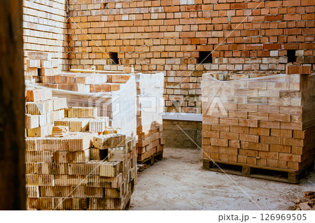 Building materials are on floor, stack red bricks. Production high-quality ceramic brick matte, reddish, porous fracture. Brick used for laying foundation. Purchase building material at hardware store Building materials are on floor, stack red bricks. Production high-quality ceramic brick matte, reddish, porous fracture. Brick used for laying foundation. Purchase building material at hardware store 126969505