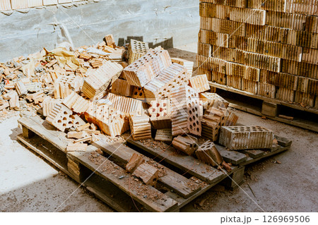 Building materials are on floor, stack red bricks. Production high-quality ceramic brick matte, reddish, porous fracture. Brick used for laying foundation. Purchase building material at hardware store 126969506