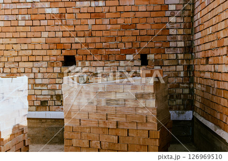 Building materials are on floor, stack red bricks. Production high-quality ceramic brick matte, reddish, porous fracture. Brick used for laying foundation. Purchase building material at hardware store 126969510