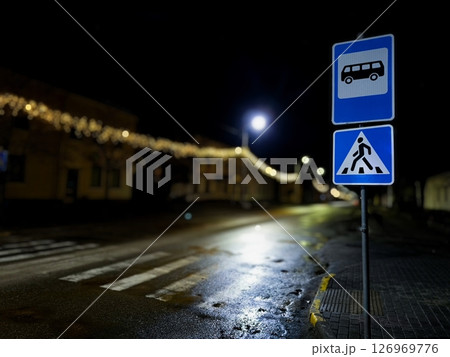 Pedestrian crossing and bus stop sign at night. 126969776