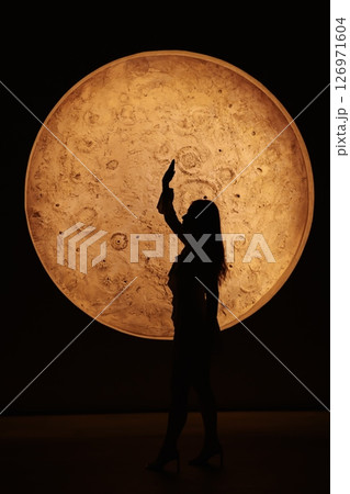 A striking silhouette set against a large, moonlike sphere creates a captivating visual 126971604