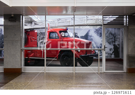 A Vintage Red Fire Truck is Beautifully Displayed Against a Backdrop of Modern Architecture 126971611
