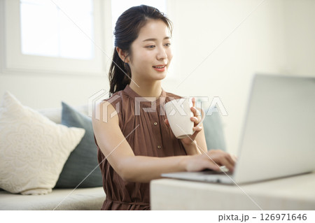 リビングでノートパソコンに向かう20代女性 126971646