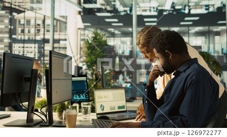 Employee in office showing revenue figures on laptop to manager. Accountant presenting company statistical numbers on notebook to supervisor after finishing job tasks, camera B Employee in office showing revenue figures on laptop to manager. Accountant presenting company statistical numbers on notebook to supervisor after finishing job tasks, camera B 126972277