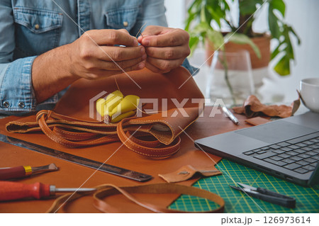 Leather craftsman sewing a bag in his workshop 126973614