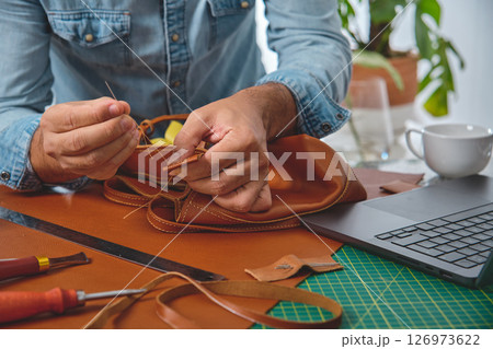 Craftsman sewing leather bag in small business workshop 126973622