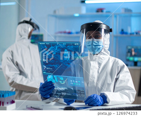 AI generated medical professional in white coat with VR glasses using transparent tablet showing glowing 3D brain hologram in clean hightech bluewhite setting 126974233