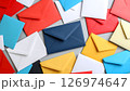 A scattered pile of colorful envelopes in red, blue, yellow, and white on a grey surface. 126974647