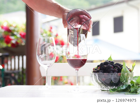 Pouring mulberry juice into glass. Pouring mulberry juice into glass. 126974975