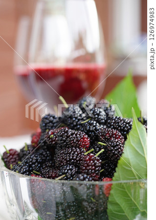 Mulberries in glass bowl with glasses of mulberry juice. 126974983