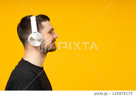 Attractive young guy listening to music in headphones Attractive young guy listening to music in headphones 126978175