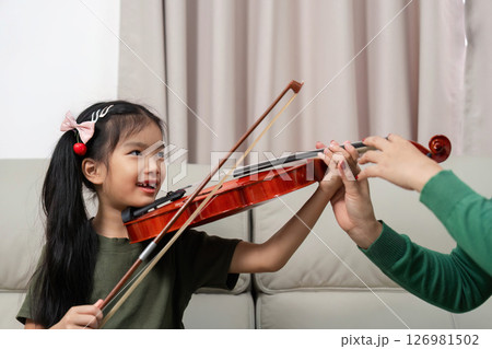Musical Bonding. A joyful child learning violin with mother at home. Musical Bonding. A joyful child learning violin with mother at home. 126981502