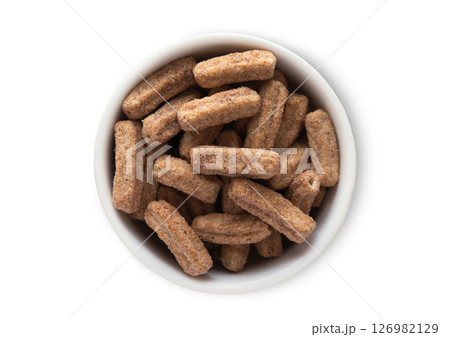Top view bowl with crunchy sweet churros sticks breakfast cereal on white.Macro. 126982129