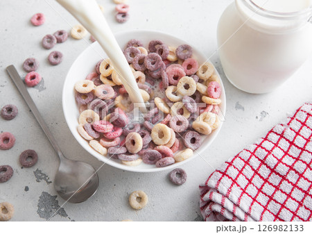 Various fruits breakfast cereal circles in plate and pouring milk into it with blueberry,banana Various fruits breakfast cereal circles in plate and pouring milk into it with blueberry,banana 126982133