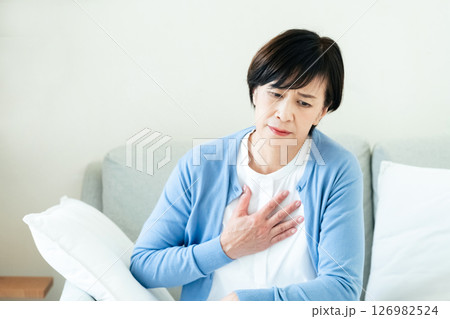 ソファで胸に手を当てる中高年女性 126982524