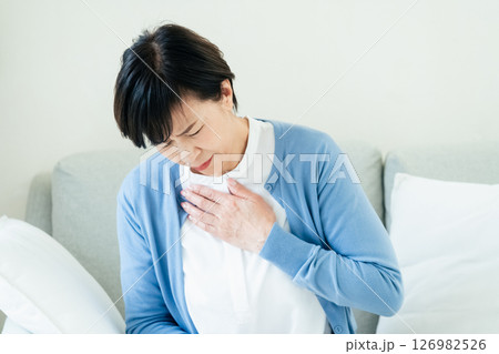 ソファで胸に手を当てる中高年女性 126982526