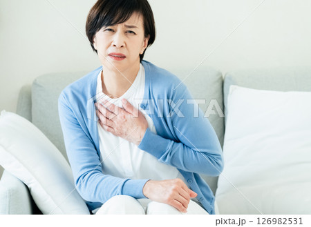 ソファで胸に手を当てる中高年女性 126982531