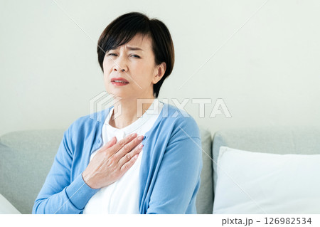 ソファで胸に手を当てる中高年女性 ソファで胸に手を当てる中高年女性 126982534