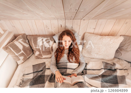 Woman Enjoying Cozy Winter Reading in Bed 126984899