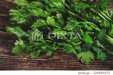 Green celeriac leaves on rustic dark wood table, view from above Green celeriac leaves on rustic dark wood table, view from above 126985075