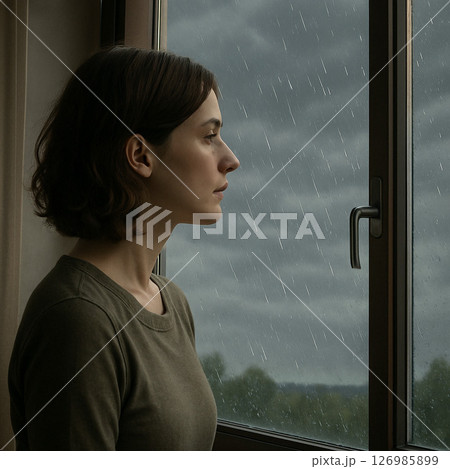 窓から雨が降る外を眺めて憂鬱そうな表情をする女性 126985899