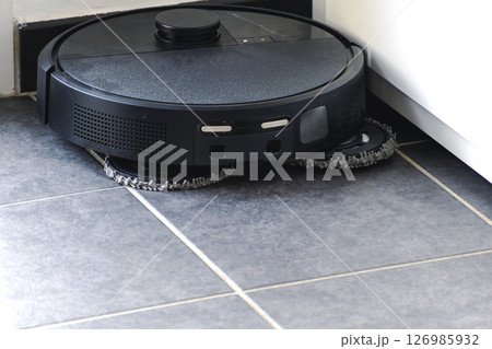 Robot vacuum cleaner with dust, real life photo, saves time and goes into hard-to-reach places 126985932