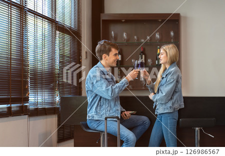 Young couple in denim outfits toasts with blue drinks in airport lounge area while waiting for their flight Young couple in denim outfits toasts with blue drinks in airport lounge area while waiting for their flight 126986567