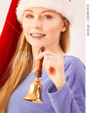woman wearing Santa Claus christmas hat holding decorative old fashioned bell. woman wearing Santa Claus christmas hat holding decorative old fashioned bell. 126987472