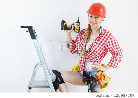 Woman wearing helmet using drill Woman wearing helmet using drill 126987504