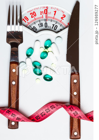 Pills with measuring tape on white scales 126989277