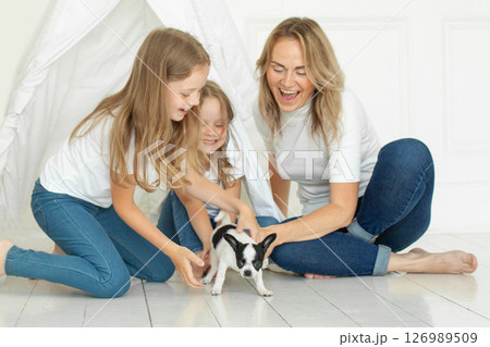Joyful family having fun with puppy dog pet at home Joyful family having fun with puppy dog pet at home 126989509
