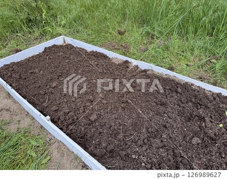 A tall garden bed with a wooden frame. Filled with fertile soil. A tall garden bed with a wooden frame. Filled with fertile soil. 126989627