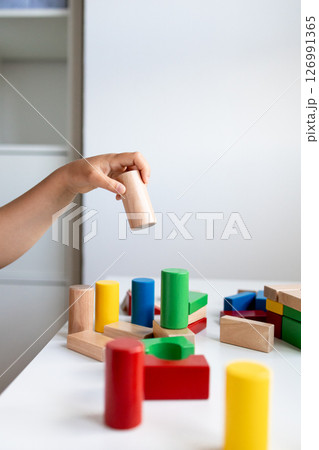 Child engaging with colorful wooden blocks for hands on play and learning Child engaging with colorful wooden blocks for hands on play and learning 126991365