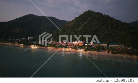 Tioman island glowing with lights at dusk, tranquil coastal scene from above Tioman island glowing with lights at dusk, tranquil coastal scene from above 126993105