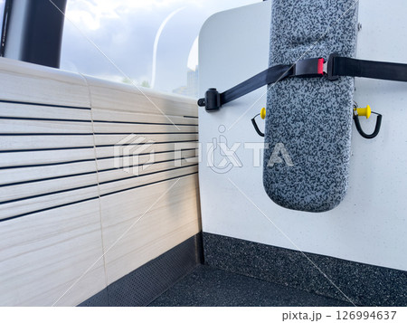 Minimalist view of a folded seat with a safety belt and wheelchair symbol in a modern public transport cabin. Clear visual indicator for accessibility and inclusive infrastructure design 126994637