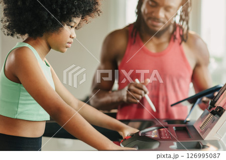 African black girl preteen athlete kid training sport activity with trainer man on treadmill in gym African black girl preteen athlete kid training sport activity with trainer man on treadmill in gym 126995087