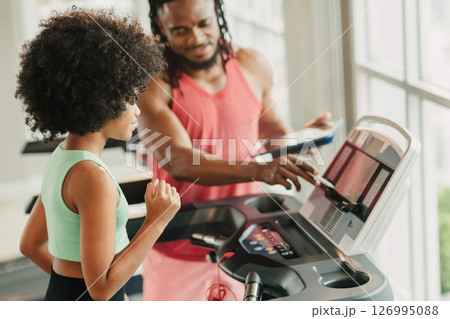 African black girl preteen athlete kid training sport activity with trainer man on treadmill in gym 126995088