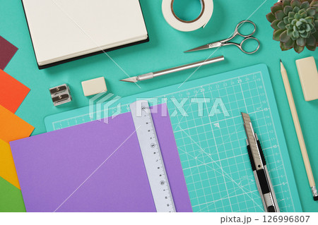 A sheet of colored paper lies on a cutting mat. Nearby are a craft knife and other items for paper crafts. A sheet of colored paper lies on a cutting mat. Nearby are a craft knife and other items for paper crafts. 126996807