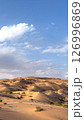 Deep blue sky meets bright dunes, forming bold visual contrast, golden desert waves rolling through sunlit terrain, capturing power of wind-sculpted sand and stillness of dry isolated nature. 126996869