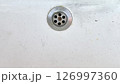 Water drain on a white surface showing signs of wear and dirt 126997360