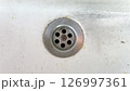 Drain opening in a sink with rust and dirt at a kitchen location 126997361