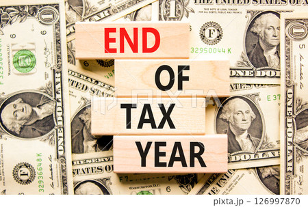 End of tax year symbol. Concept words phrase End of tax year on beautiful wooden blocks. Dollar bills. Beautiful dollar bills background. Business End of tax year concept. Copy space. End of tax year symbol. Concept words phrase End of tax year on beautiful wooden blocks. Dollar bills. Beautiful dollar bills background. Business End of tax year concept. Copy space. 126997870