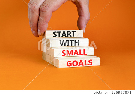 Start with small goals symbol. Concept words phrase Start with small goals on beautiful wooden blocks. Beautiful orange background Businessman's hand Business Start with small goals concept Copy space Start with small goals symbol. Concept words phrase Start with small goals on beautiful wooden blocks. Beautiful orange background Businessman's hand Business Start with small goals concept Copy space 126997871