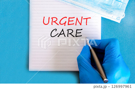 Urgent care symbol. Concept words Urgent care on beautiful white note. Doctor's hand in blue medical glove. Medical mask. Beautiful blue background. Medical healthy lifestyle urgent care concept. 126997961
