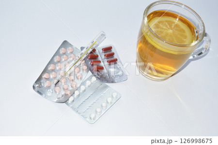 pills, thermometer and tea with lemon on white background pills, thermometer and tea with lemon on white background 126998675