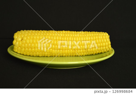 Boiled corn on a green plate on a dark background Boiled corn on a green plate on a dark background 126998684