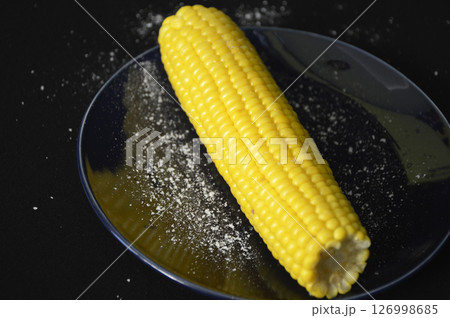 heads of boiled corn and salt on a dark plate. ready to eat delicious vegetable heads of boiled corn and salt on a dark plate. ready to eat delicious vegetable 126998685