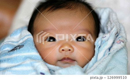Newborn chinese baby sleeping peacefully wrapped in blanket, close-up 126999510